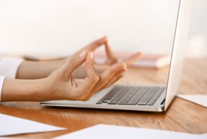 deux mains en position zen devant un ordinateur