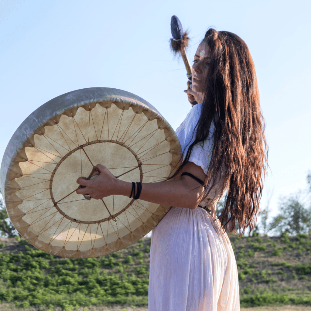 une femme joue du tambour chamanique dans la nature